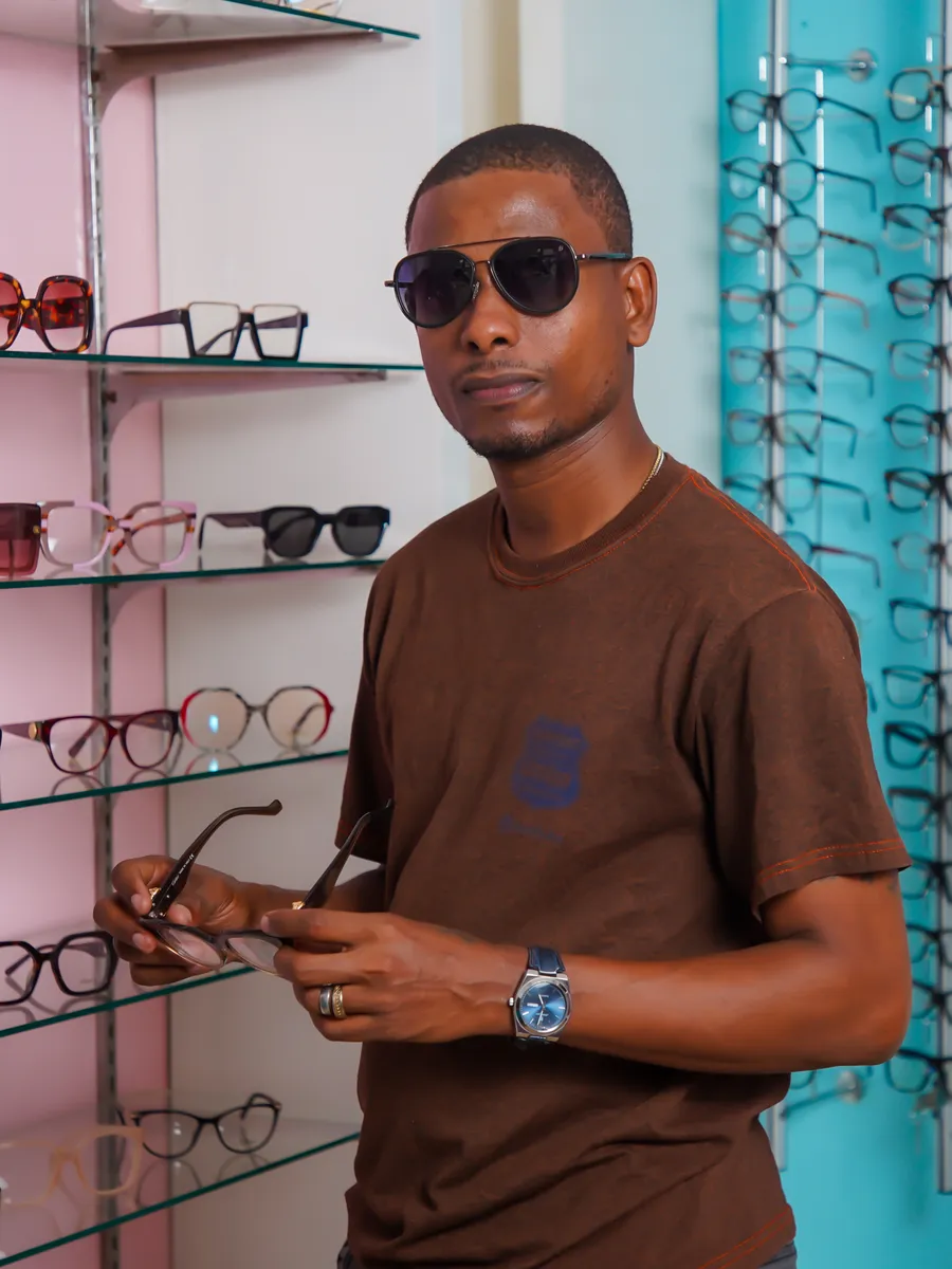 Client essayant une monture devant le mur de lunettes ORLOPHTA Optique